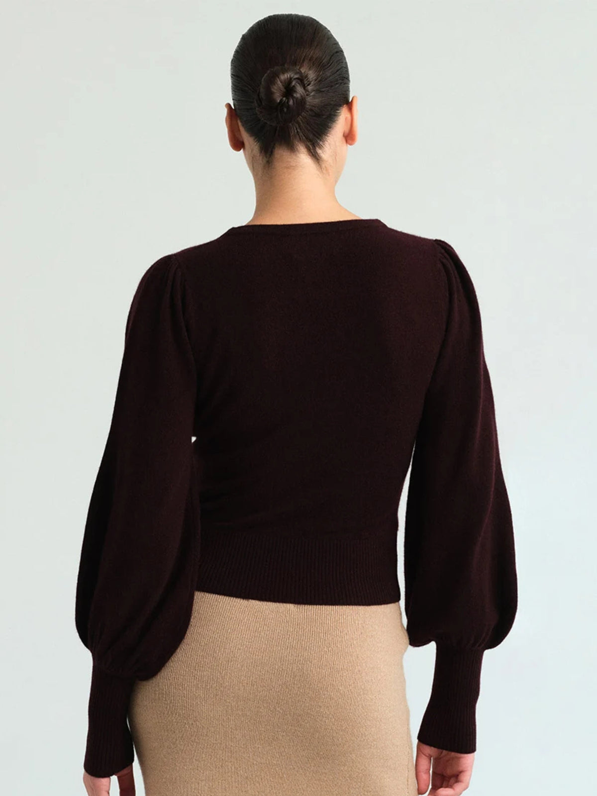 Back view of a model wearing Cara Cara Ezra Merlot top with a beige skirt.