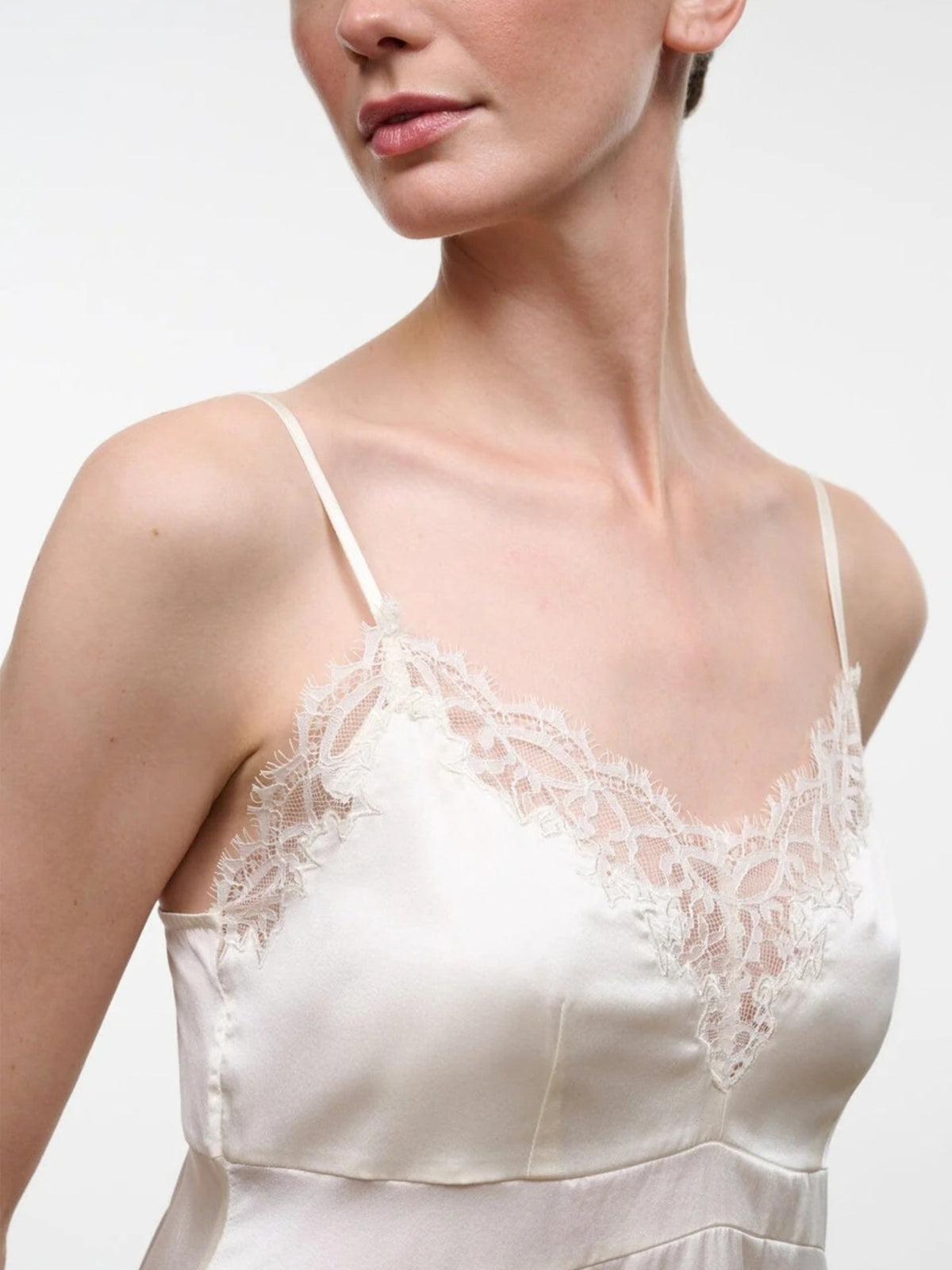 Close-up of the STAUD Lina Ivory top's thin straps and lace-trimmed neckline