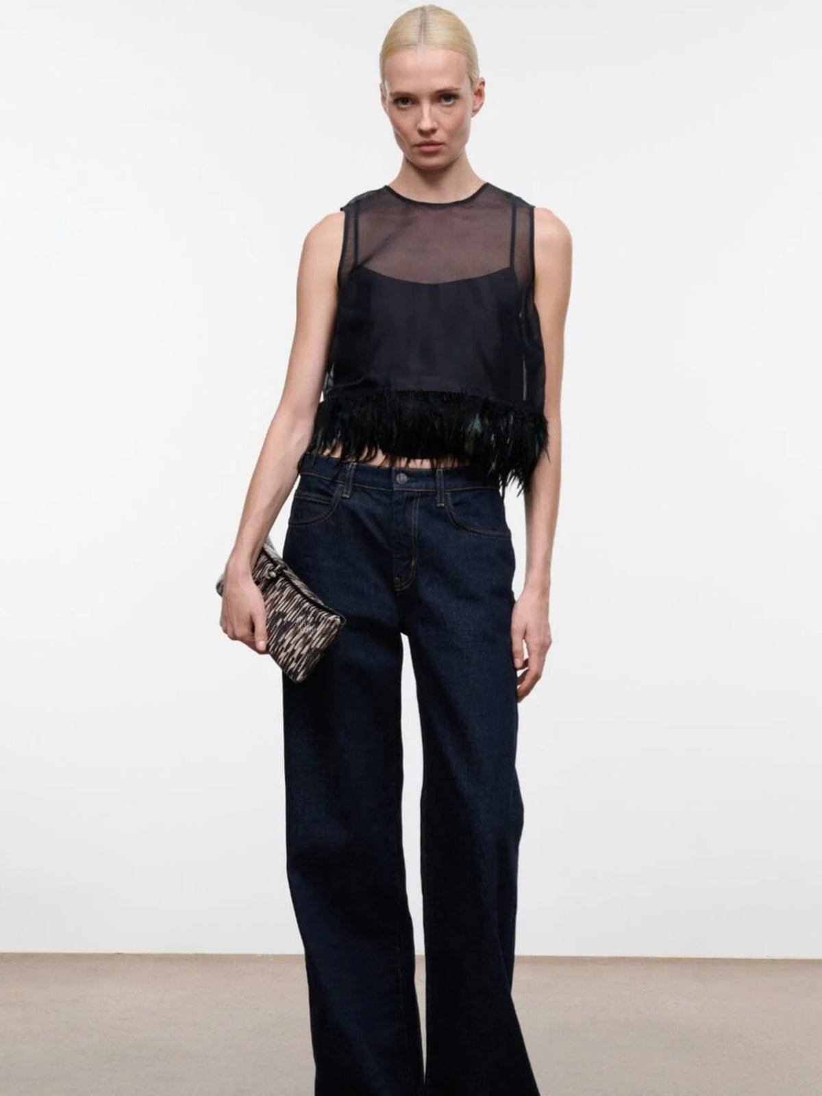 STAUD Avi Black top styled with dark jeans and a clutch, full-length front view